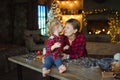 A sweet toddler kisses her grandmother in the nose, sitting on a wooden table in a hunting house decorated for Christmas, with a C Royalty Free Stock Photo