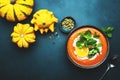 Sweet vegan pumpkin soup with coconut cream, orange and mint. Winter or autumn healthy vegetarian comfort food. Soup bowl on green