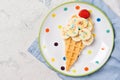 Sweet waffle with banana and strawberry in a shape of ice cream cone, meal for kids idea, top view