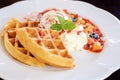 Sweet waffles with strawberries sauce vanilla ice cream fresh fruit and mint leaf on white plate Royalty Free Stock Photo