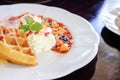 Sweet waffles with strawberries sauce vanilla ice cream fresh fruit and mint leaf on white plate Royalty Free Stock Photo