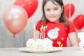 Sweet white birthday cake with candles and defocused happy little girl on the background during party celebration Royalty Free Stock Photo