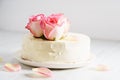Sweet white buttercream cake with pink rose flowers on top