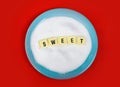 Sweet word block letters on bed of sugar in blue dish over red mat in sugar addiction Royalty Free Stock Photo