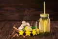 Sweet yellow beverage in a big glass jar with lemon, cinnamon, mint, ginger, and carambola on a wooden background. Copy space. Royalty Free Stock Photo