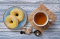 Sweet yellow donuts on a blue glazed saucer and cup of tea