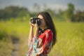 Sweet young Asian Chinese or Korean woman on her 20s taking picture with photo camera smiling happy in beautiful nature landscape Royalty Free Stock Photo