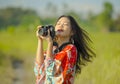 Sweet young Asian Chinese or Korean woman on her 20s taking picture with photo camera smiling happy in beautiful nature landscape Royalty Free Stock Photo