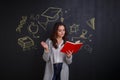 A girl reading a book, standing next to a whiteboard with a picture of science and knowledge. Royalty Free Stock Photo