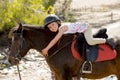 Sweet young girl hugging pony horse smiling happy wearing safety jockey helmet in summer holiday Royalty Free Stock Photo