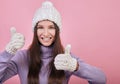Sweetly pretty girl in a knitted hat, purple sweater and mittens shows super sign or like