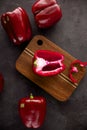 Red bell  peppers on wooden cutting board on black and dark grey background. Green pepper sliced and chopped on wooden chopping Royalty Free Stock Photo