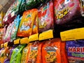 Sweets and candies in medium size commercial packs and hung for sale on display shelves.