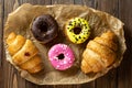 Sweets croissants donuts and cakes in wrapping paper on the table. sweet colorful bakery on a wooden background. Royalty Free Stock Photo