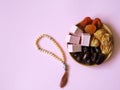 Sweets, dates, dried apricots on a plate on a pink background