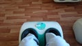 White electric foot massager on a background of linoleum with imitation laminate