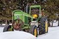 Swift Current, Saskatchewan, Canada- March 9, 2019: Vintage John Deere tractor in snow drift in Saskatchewan, Canada