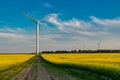 Swift Current, SK/Canada- July 29, 2019: An SUV below a wind turbine in a canola field