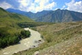 The swift mountain river of turquoise color looping bends its channel at the foot of high mountains