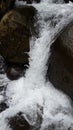 The swift water of the river forms a lot of foam against a rock background, making the river beautiful