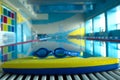 Swim board with Goggles on beside of the swimming pool in sports center. swimming training concept. copy space for text. Royalty Free Stock Photo