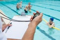 Swim coach looking at stopwatch near poolside