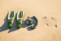 Swim flippers with snorkel, mask and feet steps on a sandy beach. Water sports. Snorkeling. Travel and holiday concept. Fins and s Royalty Free Stock Photo