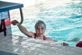 Swimmer girl holding rail of starting block in swimming pool, young sportsman
