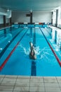 The swimmer pushes off the edge of the swimming pool. woman athlete jumps into the water indoors. Stopping in motion. View from Royalty Free Stock Photo