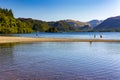 Swimmers in a calm lake surrounded by mountains on a hot summers day Royalty Free Stock Photo