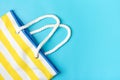 Swimming accessories - trendy beach bag with yellow and white stripes on blue background Royalty Free Stock Photo