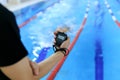 Swimming coach holding stopwatch poolside at the leisure center.