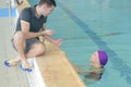 Swimming coach holding stopwatch poolside at leisure center