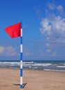 Swimming is dangerous in ocean waves. Red warning flag flapping in the wind on beach at stormy weather Royalty Free Stock Photo