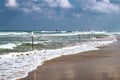 Swimming is dangerous in sea waves. Red warning flag flapping in the wind at stormy weather on the beach Royalty Free Stock Photo