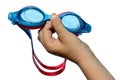 Swimming goggles held in small boy left hand on white background, with drops and traces of salt water on it Royalty Free Stock Photo
