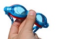 Swimming goggles held in small boy left hand on white background, with drops and traces of salt water on it Royalty Free Stock Photo