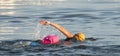 Swimming in the open water with pink flotation device for safety