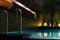 Swimming pool area at night with soft glowing outdoor lighting in expensive home in tropical southeast asia with flat water and ro Royalty Free Stock Photo