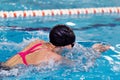 Swimming pool athlete training indoors for professional competition. Female swimmer performing the breaststroke at Royalty Free Stock Photo