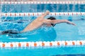 Swimming pool athlete training indoors for professional competition. Teenager swimmer performing the butterfly stroke at Royalty Free Stock Photo