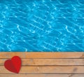 Swimming pool with blue clear water, wooden deck and red paper