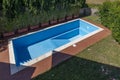 A swimming pool with blue coating in a private garden is completely empty, waiting to be filled with water Royalty Free Stock Photo