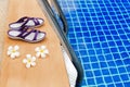 Swimming pool, blue water, white plumeria frangipani flowers, women flip flops, poolside, tropical sea beach, summer holidays Royalty Free Stock Photo