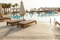 Swimming pool with chaise lounge and sunshade at tropical resort Royalty Free Stock Photo