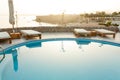 Swimming pool with chaise lounge and sunshade at tropical resort Royalty Free Stock Photo