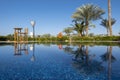 Swimming pool with clear blue water, palm trees and blue sky. Summer luxury resort. Royalty Free Stock Photo