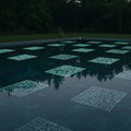 Swimming pool with dark water reflecting trees, featuring glowing QR code patterns Royalty Free Stock Photo