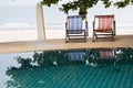 Swimming pool and deck chair under coconut palm trees at the resort with beautiful sea view Royalty Free Stock Photo