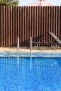 Swimming pool design modern architecture of luxury holiday villa. Relax near exotic swimming pool with handrail, deck chairs, sun. Royalty Free Stock Photo
